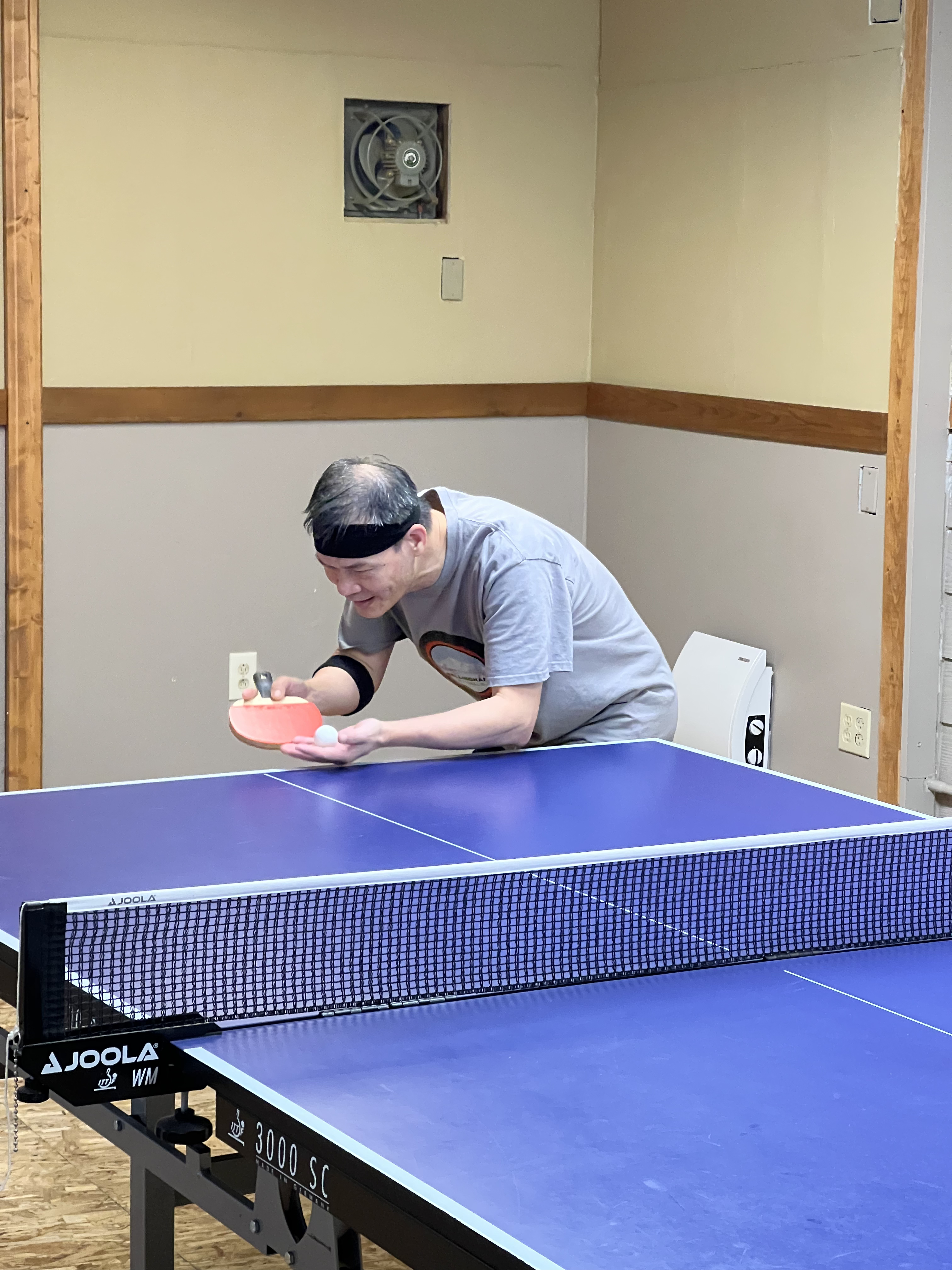 A table tennis serve action shot at Bellingham Table Tennis Club